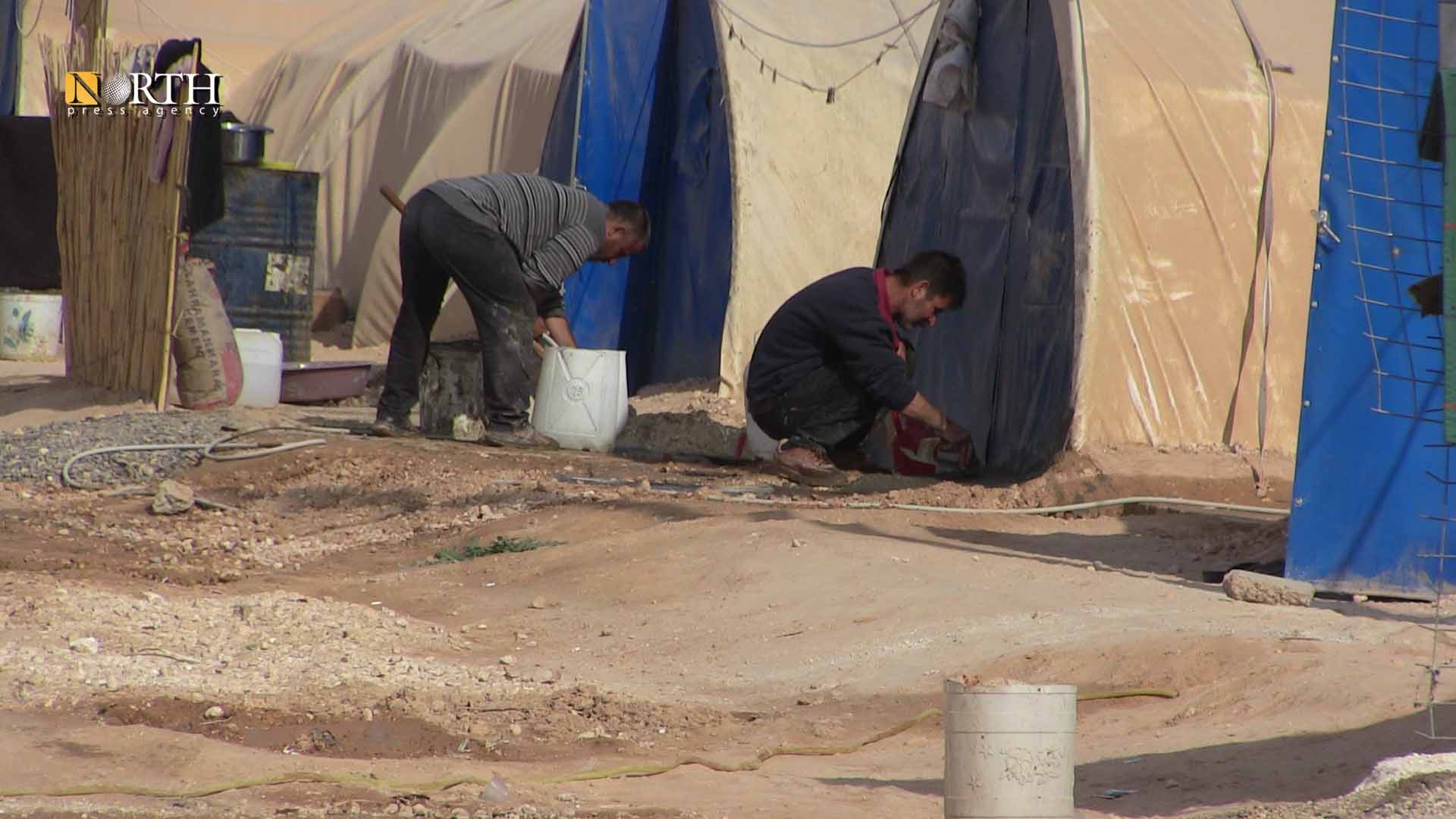 An IDP in a camp in Raqqa puts sand and dust around his tent in order to protect it from rain – North Press