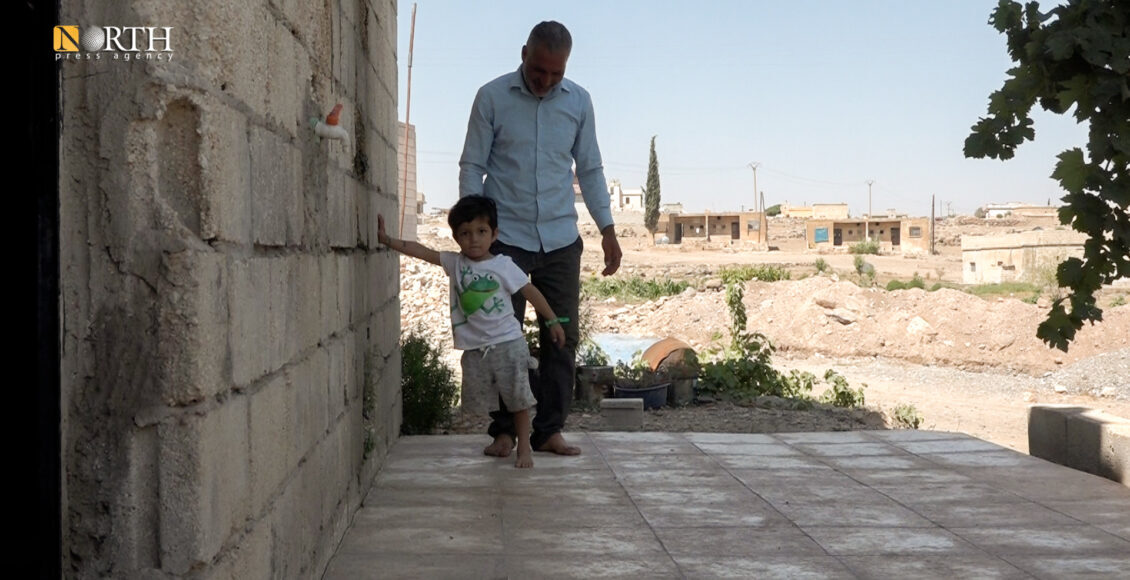 The child Abdo Henifi with his father at their house in Syria’s Kobani – North Press