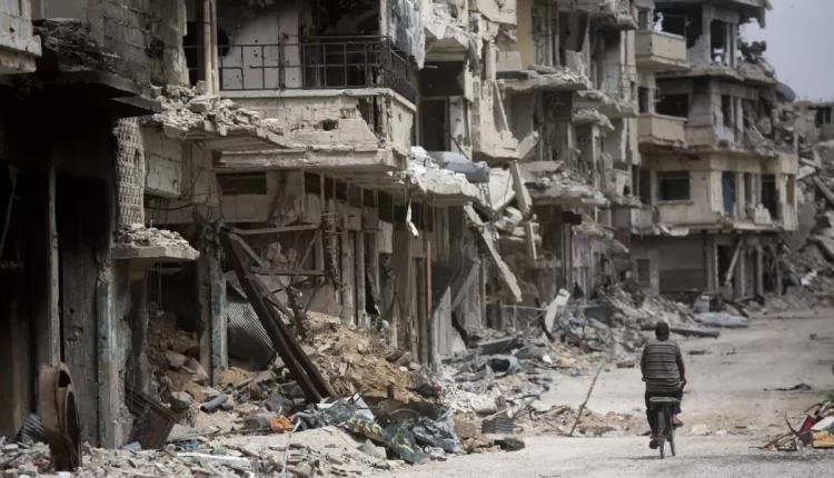 A man rides a bicycle through a devastated part of Homs, central Syria, on June 5, 2014 – AP