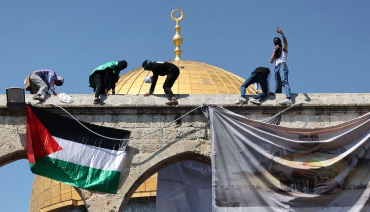 Palestinian youth hang their flag in front of the al-Aqsa mosque – AFP
