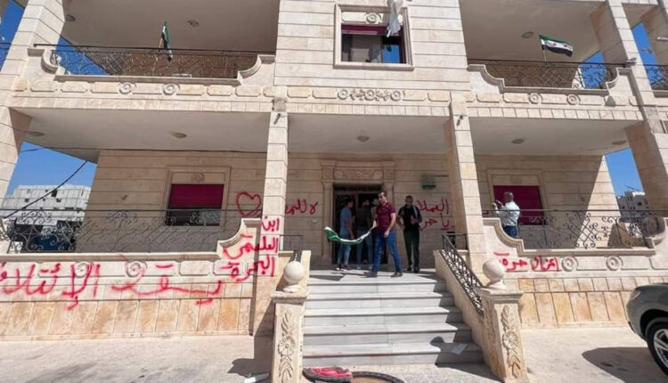 Protestors writing slogans against the Syrian National Coalition (SNC), affiliated with the Syrian opposition, on its office in the city of Azaz, north Syria