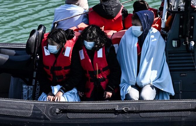 Migrants are seen on the UK Border Force rubber dinghy, after they were picked up at sea while attempting to cross the English Channel – AFP