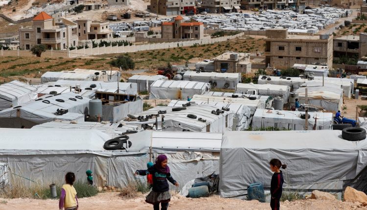 Syrian refugee children play at an informal refugee camp, which is seen set between the houses and buildings in Arsal, near the border with Syria, east Lebanon, June 13, 2018 - AP