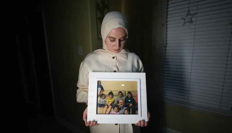 Maryam Kamalmaz holding a photo of her father with grandchildren in Texas on Jan. 17, 2024 – AP