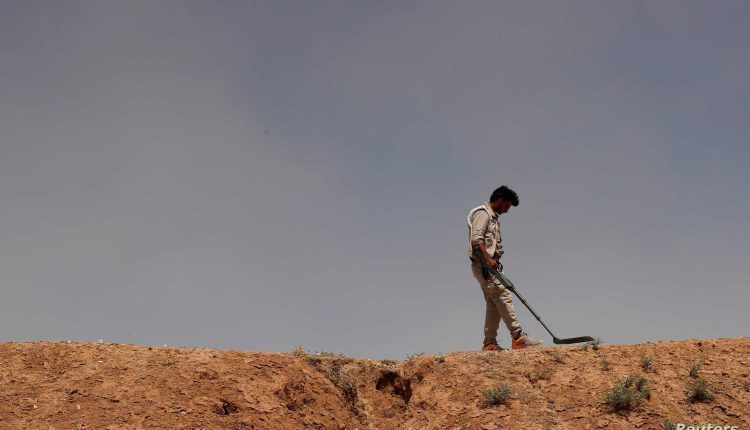 A member of Roj Mine Control Organization searches for mines and explosive devices planted by ISIS militants near the town of Ain Issa in the north of Raqqa, northern Syria, June 20, 2017 - Reuters