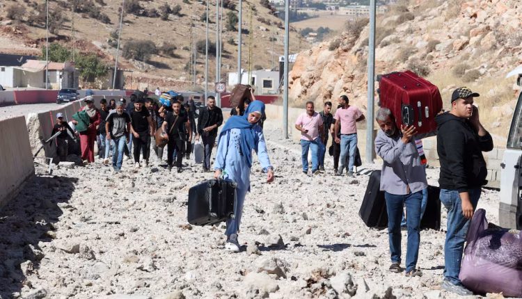People carry their belongings while walking on the rubble after an Israeli strike on Masnaa border crossing between Syria and Lebanon on Oct. 4, 2024 – Reuters
