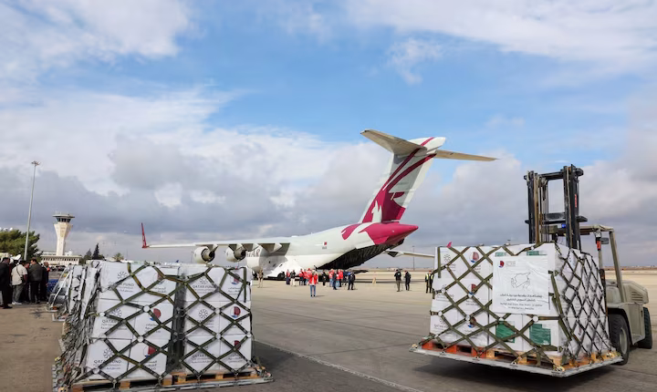 People stand near a plane carrying aid from Qatar, as it arrives at Damascus International Airport, Syria, on Dec. 30, 2024 – Reuters
