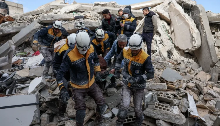 In this February 2023 photo, members of the Syrian civil defense, known as the White Helmets, transport a casualty from the rubble of buildings in the village of Azmarin, in Syria's Idlib following an earthquake. Omar Haj Kadour/AFP/Getty Images