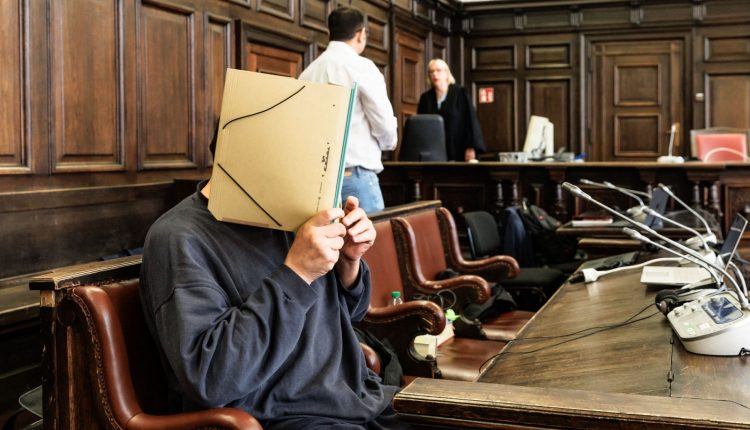 A defendant accused of contributing to war crimes of a Syrian Shabiha pro-Assad militia hides his face as he waits for his trial in Hamburg, northern Germany, on May 17, 2024. – AFP