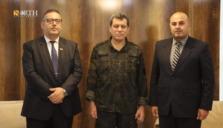 SDF Commander Mazloum Abdi receiving Kobani district head Ibrahim Muslim (on the left) and former AANES official Anwar Muslim (on the right) in Hasakah city on May 16, 2026. – North Press