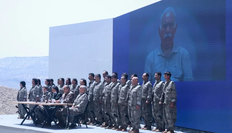 PKK commanders and fighters stand in front of a picture of jailed leader Abdullah Ocalan during a ceremony in Sulaymaniyah in Iraq's Kurdistan Region on July 11, 2025. – AFP