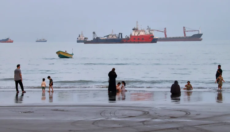 People spend time at a beach as commercial vessels are anchored in the Strait of Hormuz off Bandar Abbas, Iran, Aug. 5, 2026. – AP