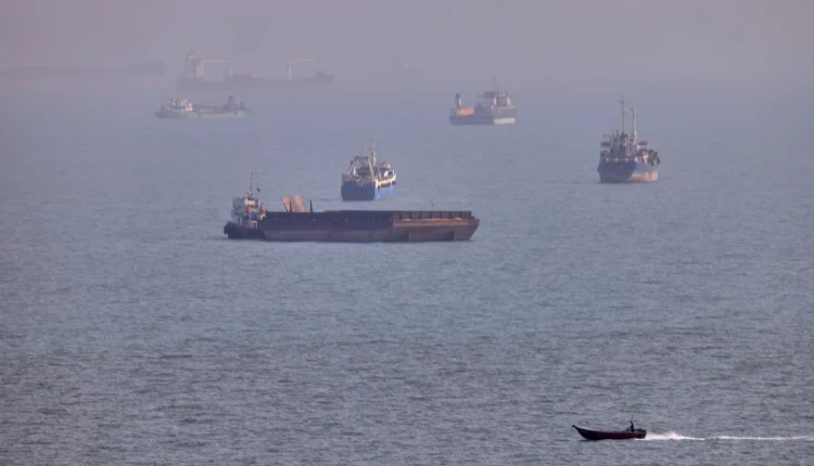 A small boat sails past cargo ships and other commercial vessels anchored in the Strait of Hormuz off Bandar Abbas, Iran, on Aug. 5, 2026. – AP