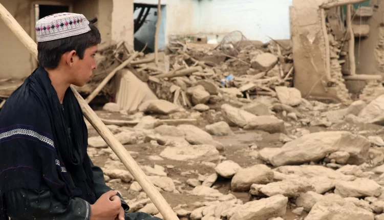 دانیشتوویەکی ئەفغانی لە تەنیشت ماڵەکەی دانیشتووە کە بەهۆی لافاوە زیانی بەرکەوتووە-ئینتەرنێت