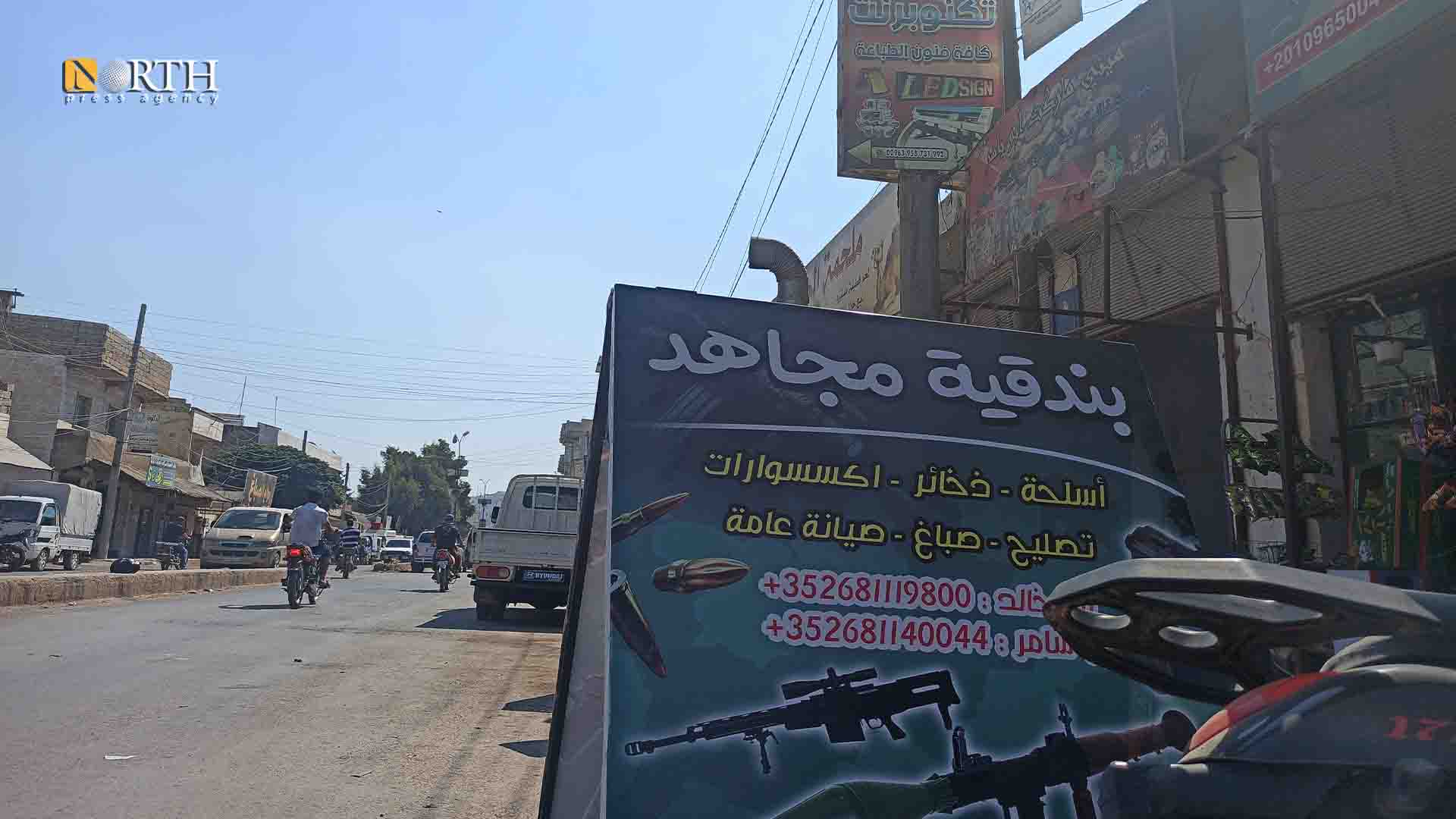 إدلب - لافتة لمحل بيع أسلحة بمدينة إدلب - نورث برس