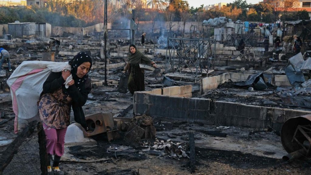 لاجئتان سوريتان تجمعان ما تبقى من أغراضهما من مخيم المنية المحترق شمال لبنان /AFP