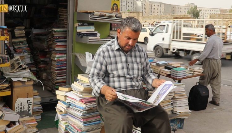رجل يقرأ صحيفة أمام مكتبة لبيع الكتب و الجرائد في مركز مدينة أربيل- نورث برس