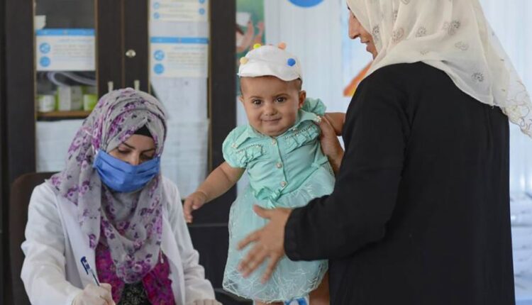 امرأة تحضر حفيدتها البالغة من العمر ثمانية أشهر لإجراء فحص طبي في عيادة صحية في ريف حماة الشمالي - موقع اليونيسف