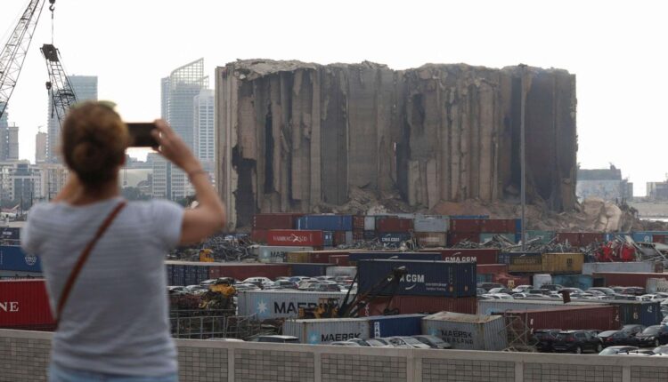سيدة تلتقط صورة لبقايا صوامع القمح في مرفأ بيروت – انترنيت / تعبيرية