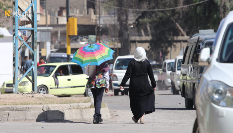 فتاة تحمل مظلة في أجواء حارة بحي مرشو وسط مدينة الحسكة - نورث برس