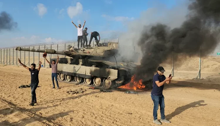 صورة متداولة لفلسطينيين أمام دبابة تم تعطيبها خلال الهجمات في محيط غزة - إنترنت