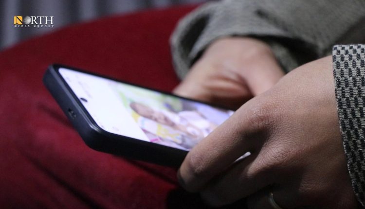 والدة فاطمة وأسينات تنظر لصور طفلتيها - نورث برس 