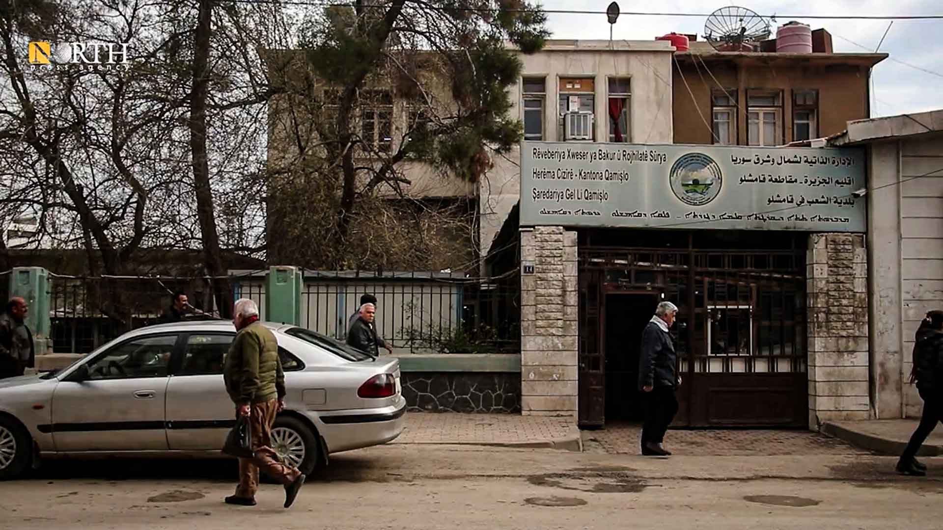 سكان يمرون أمام مبنى بلدية القامشلي – نورث برس / أرشيفية