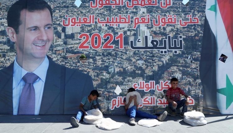 أطفال يبيعون الخبز امام ملصق دعائي لبشار الأسد – رويترز