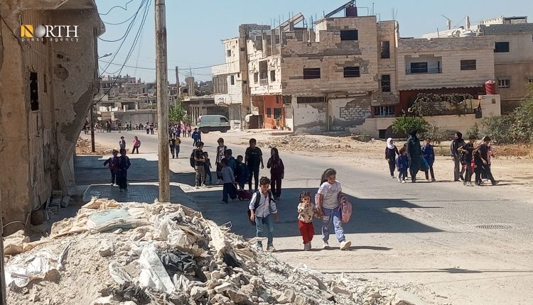 طلاب مدارس في درعا يسيرون وسط دمار خلفتها الحرب، في مشهد يجسد التحديات اليومية للعيش والتعليم - نورث برس