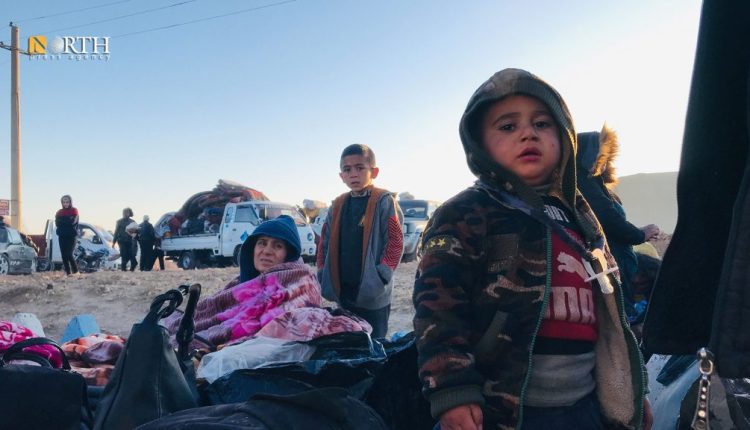 طفلان بجانب والدتهما ممن نزحوا من ريف حلب الشمالي إلى مناطق الإدارة الذاتية عقب هجوم فصائل موالية موالي لتركيا على بلدة تل رفعت - نورث برس