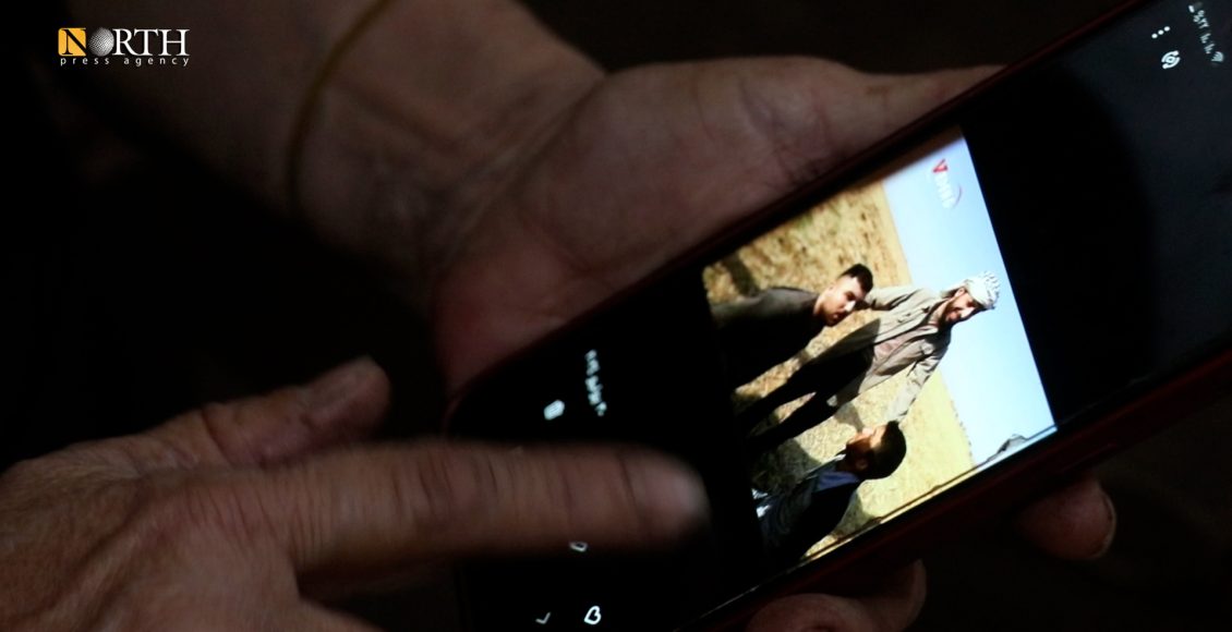 عائلة آزاد عثمان تنظر لصورة "أبو حاتم شقرا" وهو يكبل ابنها ومحمد علاء عقب الهجوم التركي على منطقتي سري كانيه وتل أبيض عام 2019 - نورث برس
