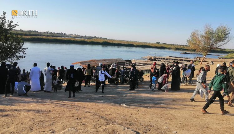 سكان من ريف دير الزور على ضفة الفرات ينتظرون عبارة تقلهم إلى الطرف الآخر – نورث برس