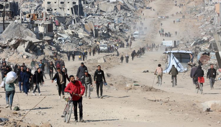 فلسطينيون يسيرون في أحد شوارع جباليا بين أنقاض المباني المدمرة في قطاع غزة - أ ف ب