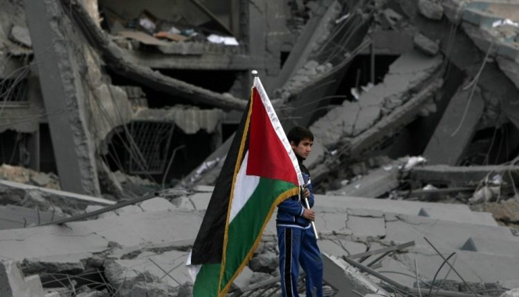 طفل يحمل علم فلسطين فوق أنقاض منزله الذي دمُر نتيجة قصف إسرائيلي على قطاع غزة - وكالة "الرأي" الفلسطينية